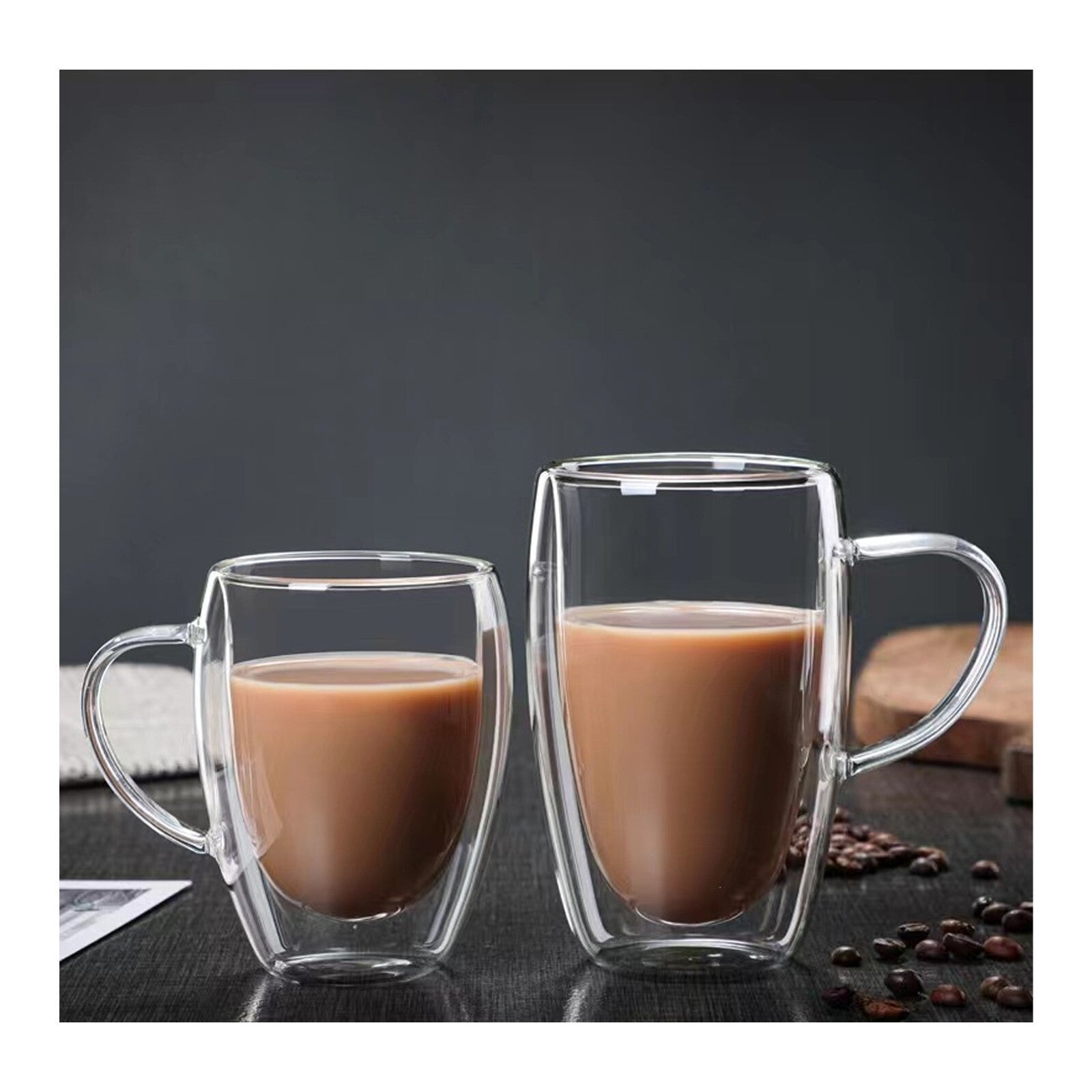 Two clear glass mugs with handles, filled with a brown liquid, on a dark surface with coffee beans.