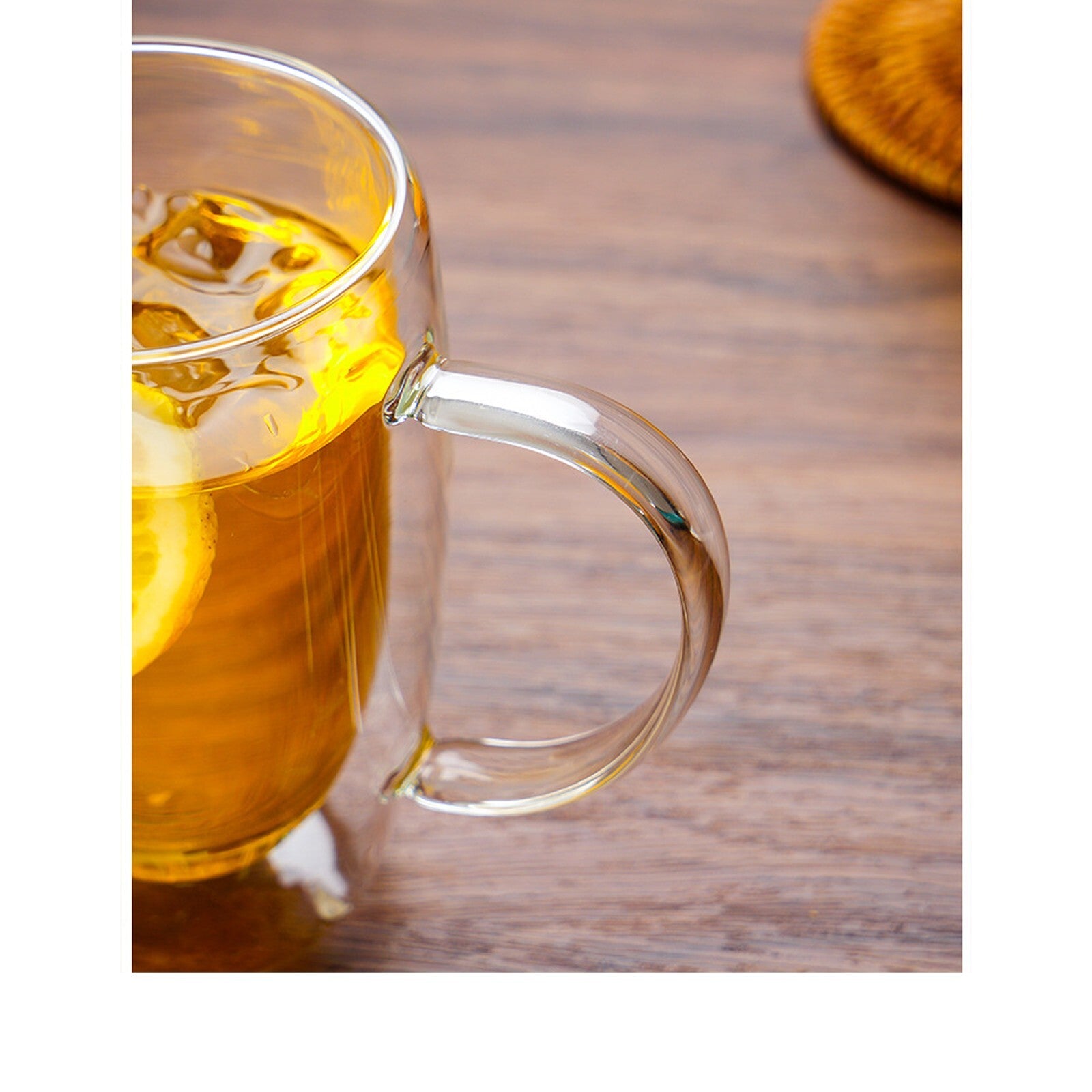 Clear glass mug with tea and lemon on a wooden surface